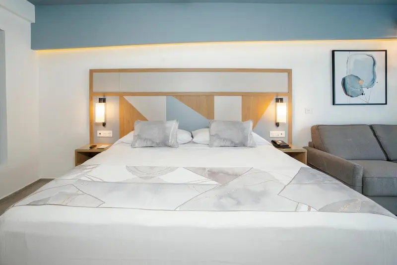 Une chambre lumineuse avec un grand lit et un coin salon.