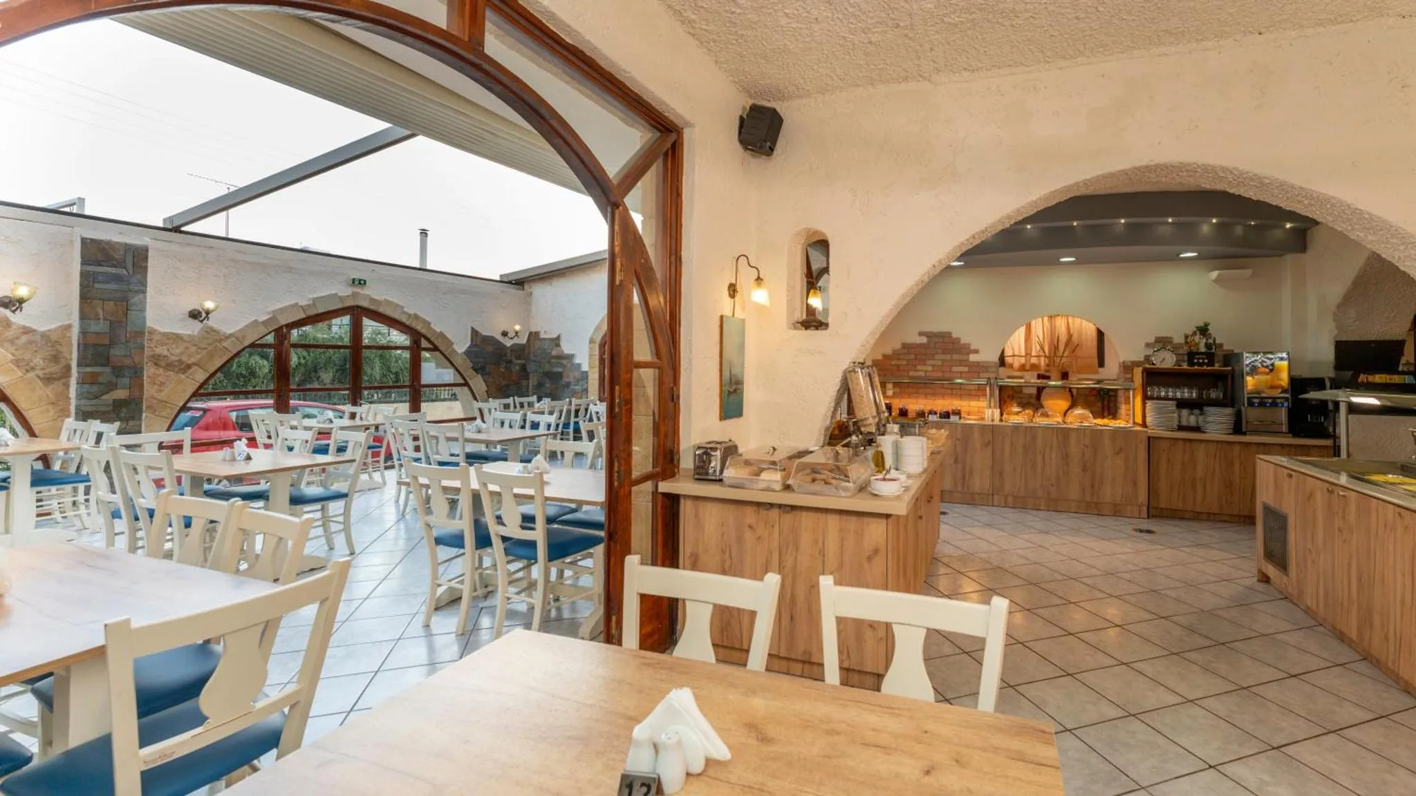 Une salle lumineuse avec des tables et des chaises, un buffet de nourriture et un comptoir de service.