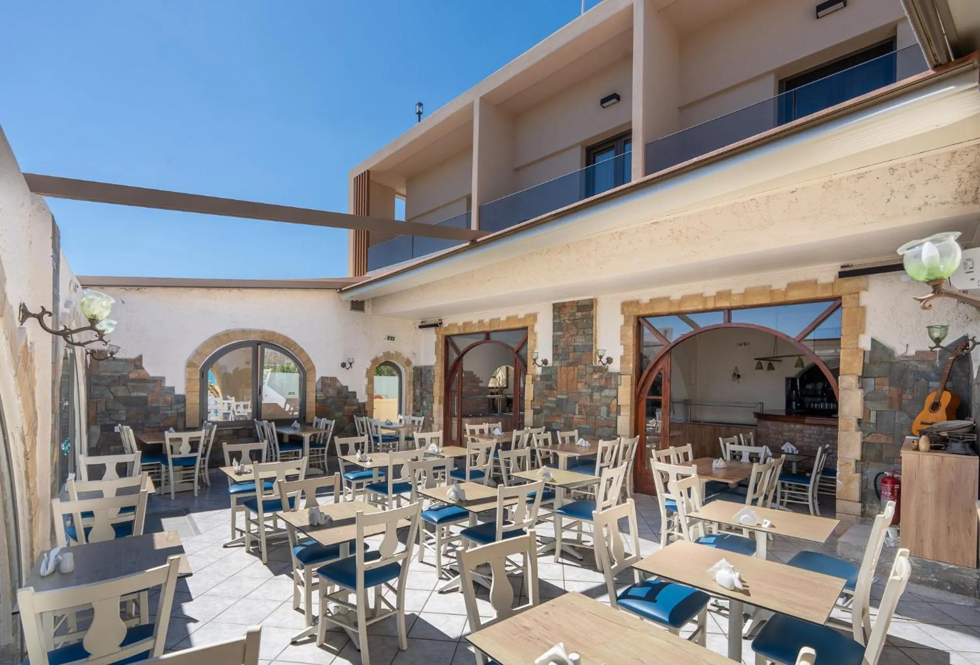 Terrasse ombragée avec tables et chaises disposées pour les repas.