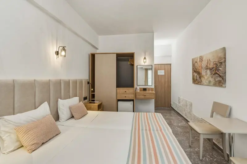 Une chambre lumineuse avec un grand lit et un coin repos.