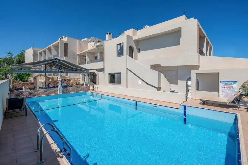 Vue d'une piscine devant un bâtiment blanc avec des balcons.