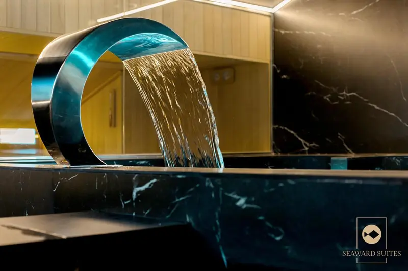 Une cascade d'eau s'écoule dans un bassin sombre et élégant.