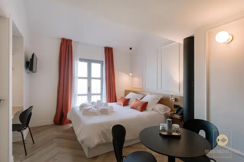 Chambre lumineuse avec un lit double et un coin repas.