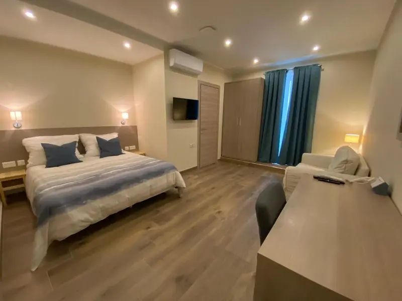 Une chambre lumineuse avec un grand lit et un espace détente.