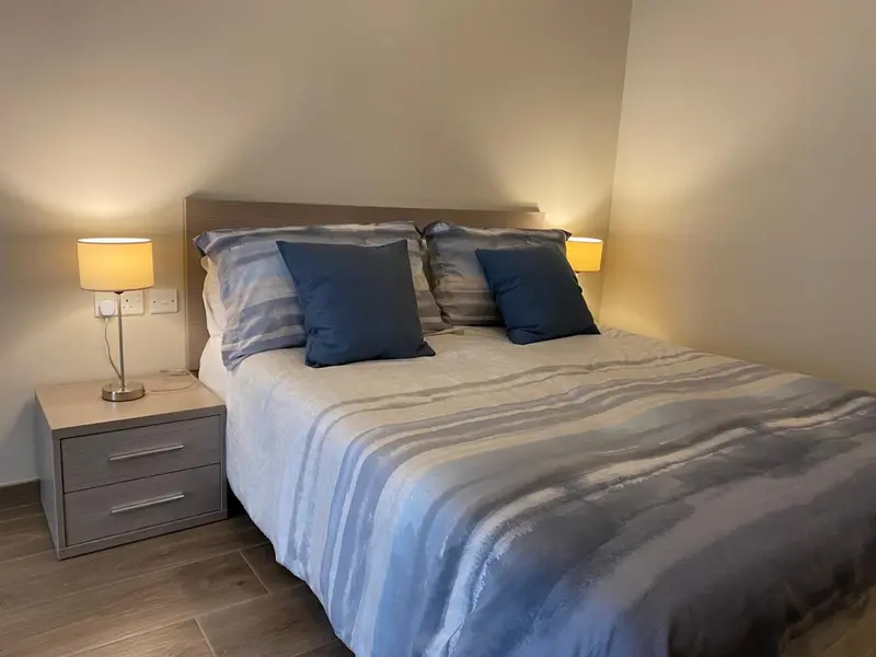 Une chambre lumineuse avec un grand lit recouvert d'une couette rayée.