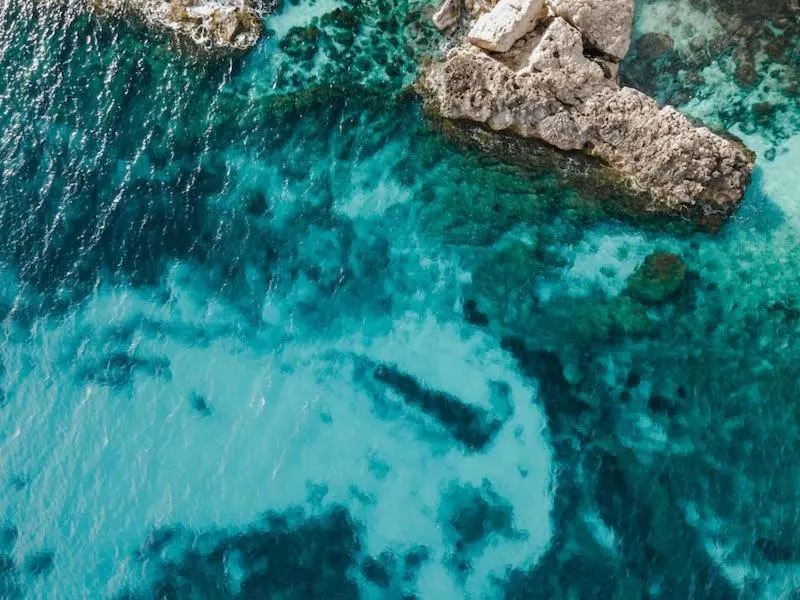 Vue aérienne d'une côte rocheuse et d'eaux turquoise claires.