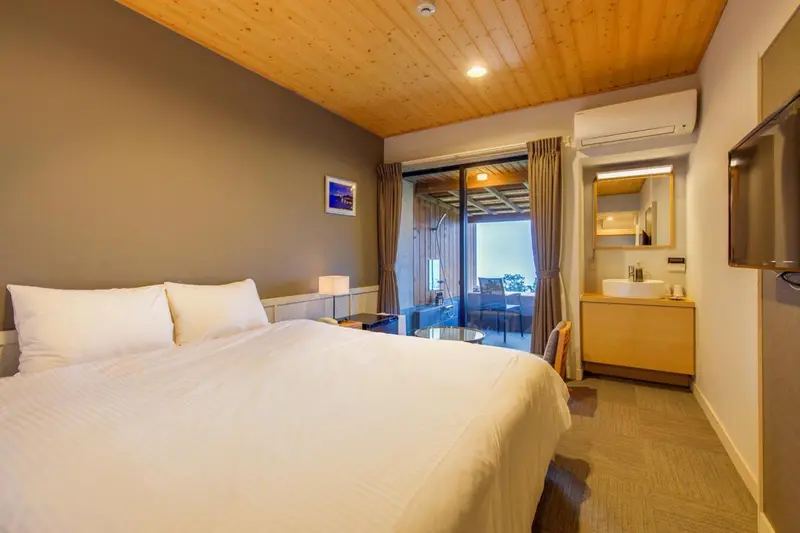 Une chambre lumineuse avec un grand lit et un accès à une terrasse.