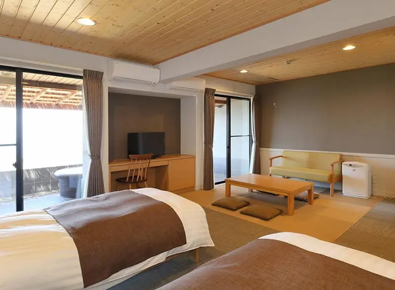 Une chambre lumineuse avec un lit, un bureau et un coin salon.