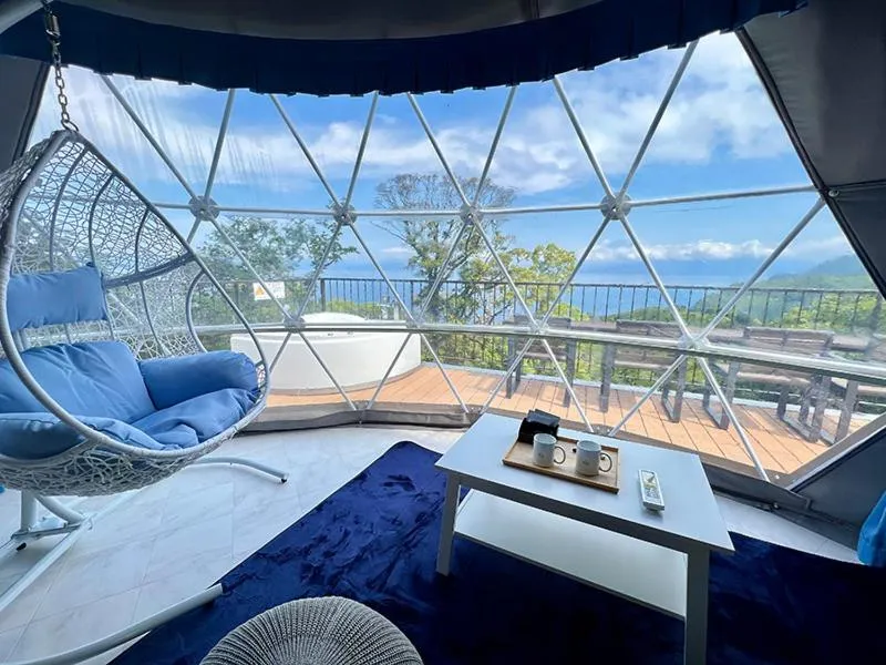 Espace de détente intérieur avec fauteuil suspendu et vue sur la mer.