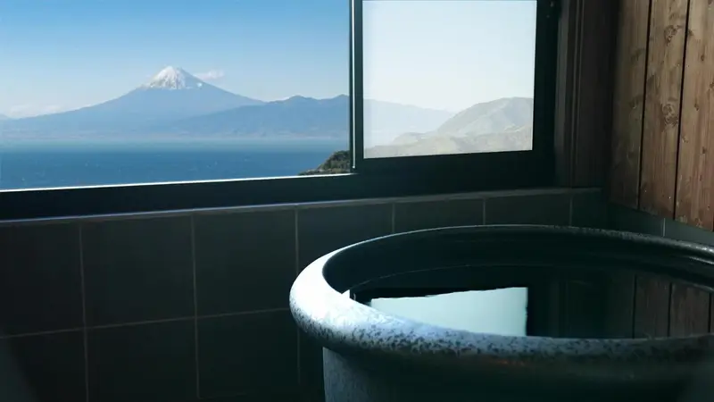 Baignoire en bois donnant sur une vue montagneuse et maritime.