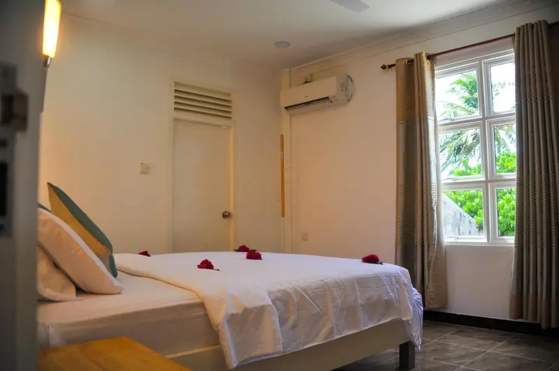 Une chambre lumineuse avec un lit décoré de pétales de fleurs.