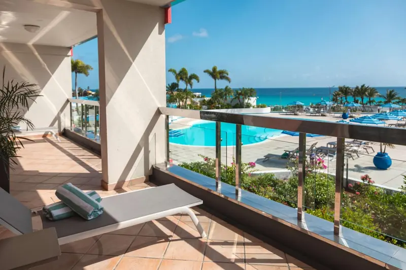 Terrasse carrelée avec transat donnant sur une piscine et la mer.