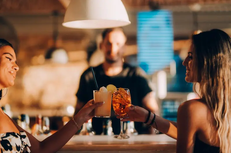 Deux femmes trinquent avec des cocktails dans un bar.