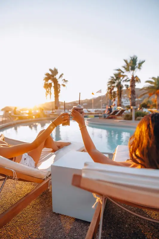 Des personnes se détendent au bord d'une piscine ensoleillée avec des boissons.
