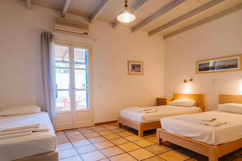 Une chambre lumineuse avec deux lits simples et une fenêtre ouverte.