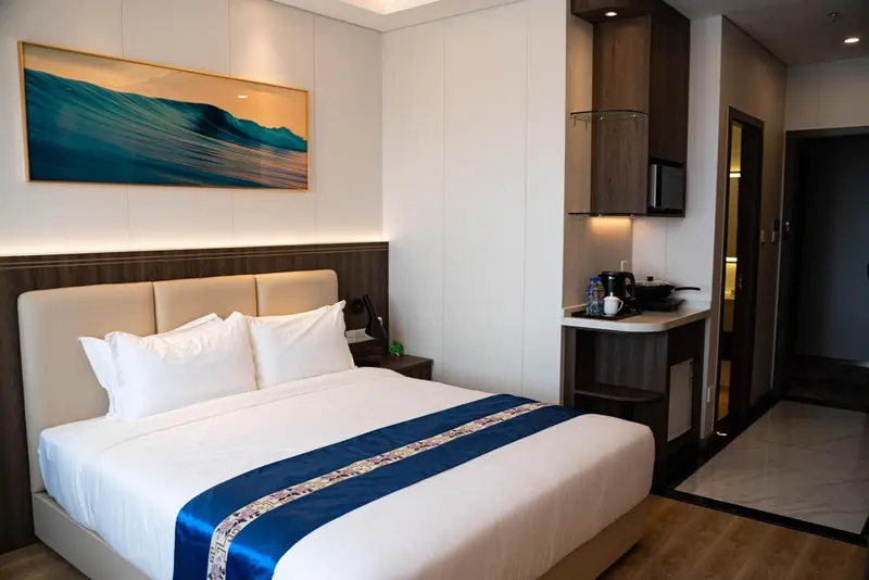 Une chambre lumineuse avec un grand lit et un coin cuisine.