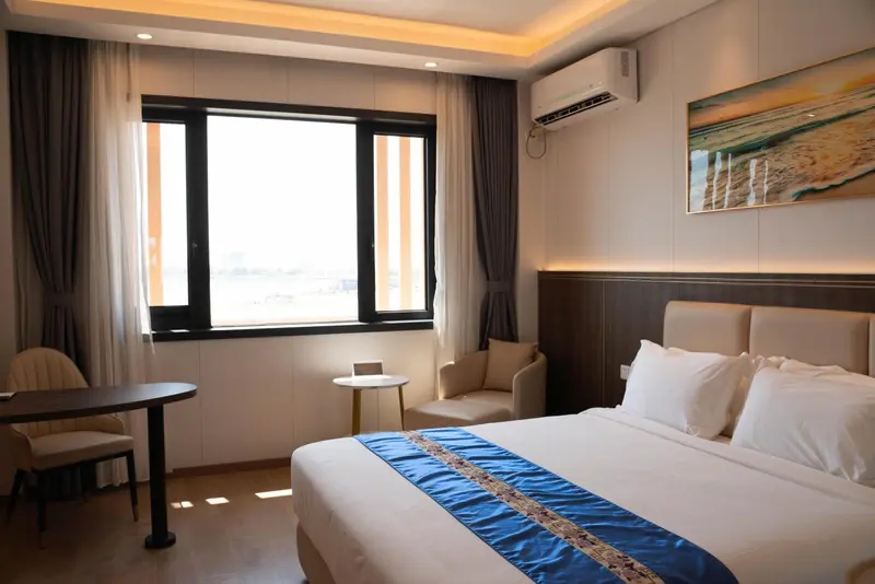 Une chambre lumineuse avec un lit double et un coin salon près d'une fenêtre.