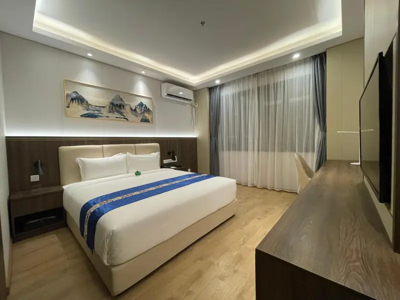 Chambre lumineuse avec un grand lit et des rideaux blancs.