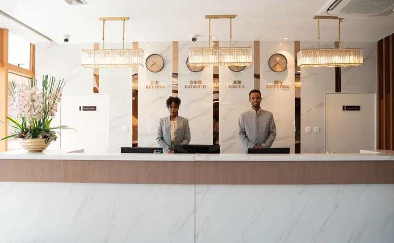Deux employés accueillent les clients derrière un comptoir d'enregistrement.
