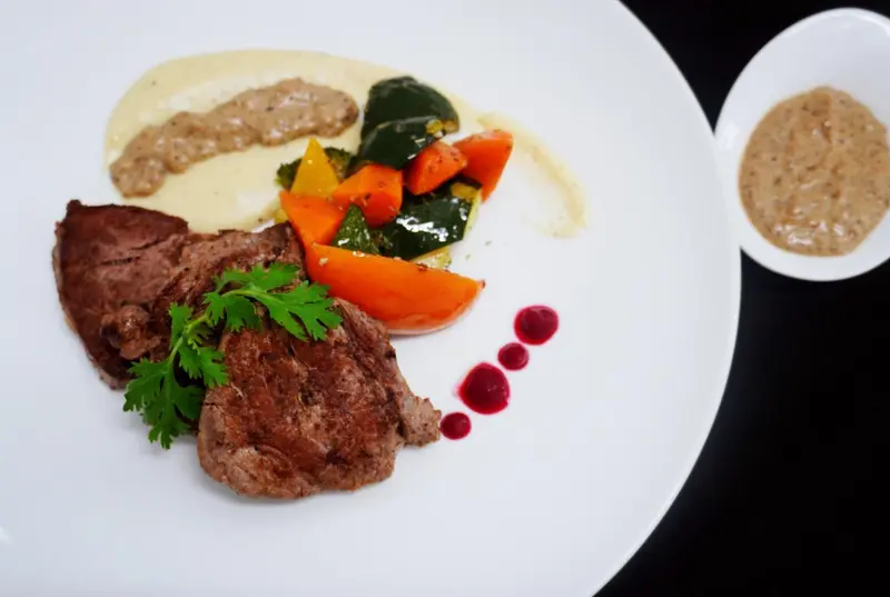 Assiette de viande accompagnée de légumes et de sauces.