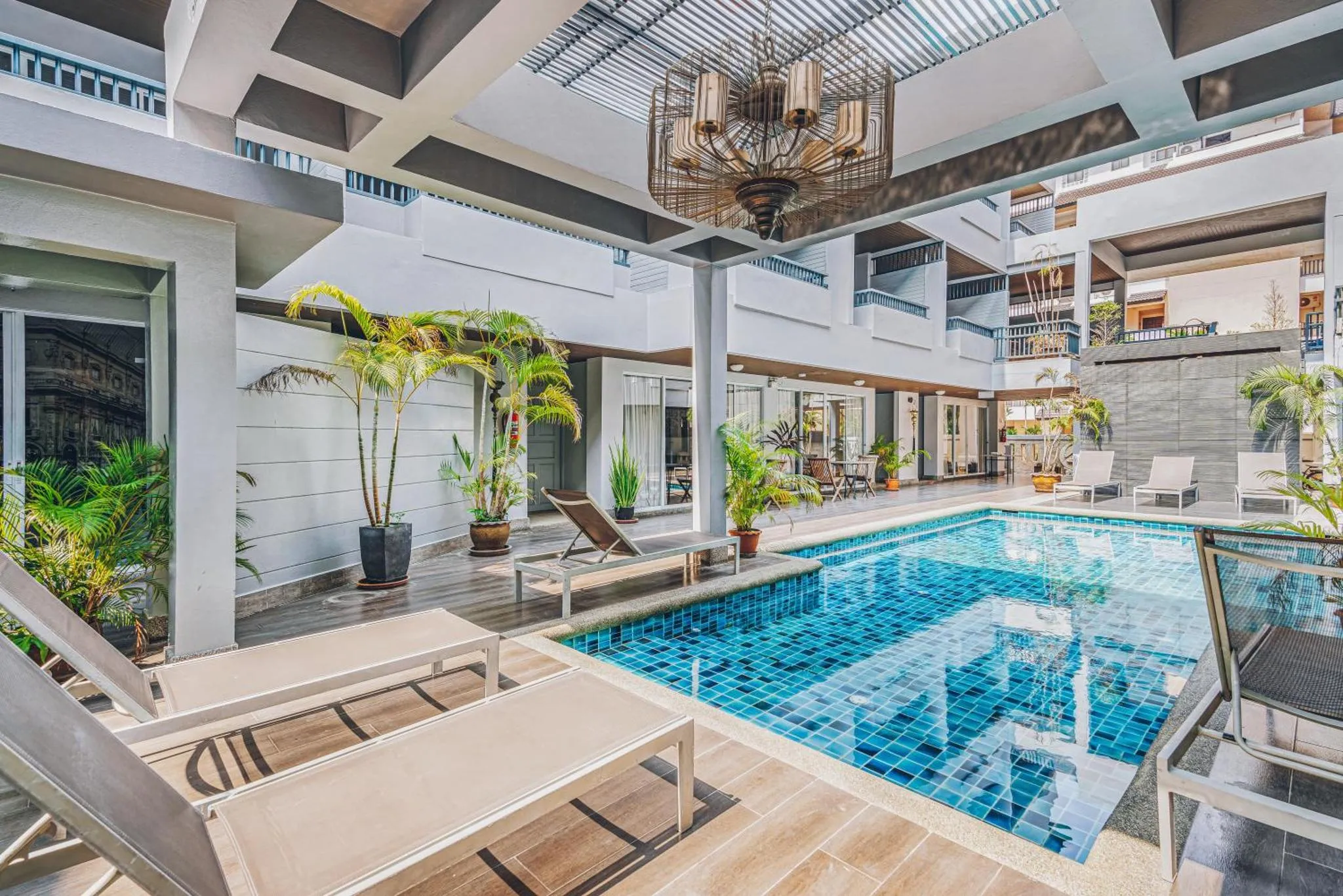 Espace piscine extérieur avec chaises longues et végétation tropicale.