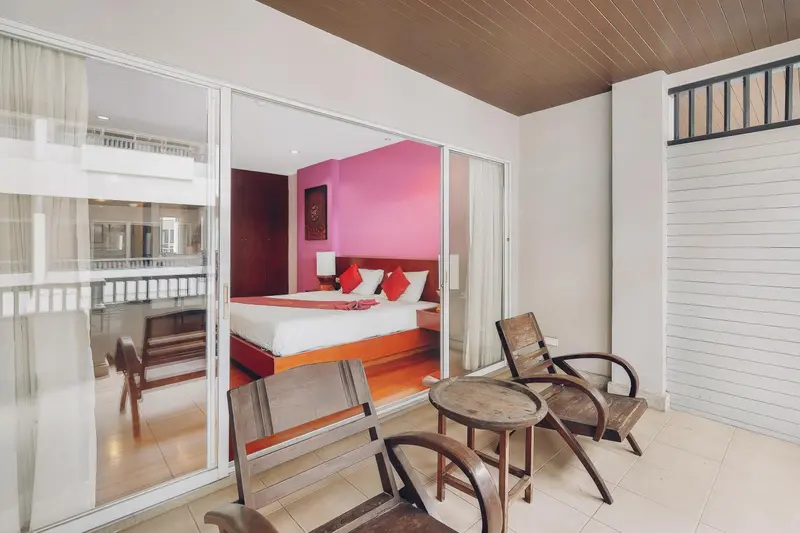 Une chambre lumineuse s'ouvre sur une terrasse avec des fauteuils.