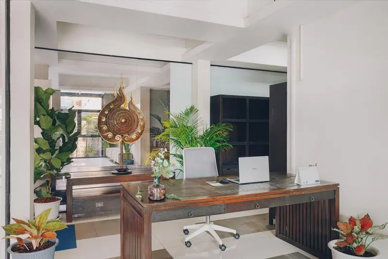 Un comptoir d'accueil en bois est décoré de plantes et d'objets d'art.