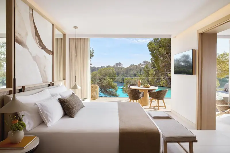 Une chambre lumineuse avec un grand lit et une vue sur la végétation et une piscine.