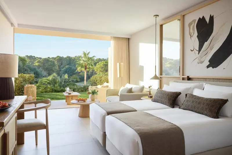 Une chambre lumineuse avec un grand lit et vue sur la végétation.