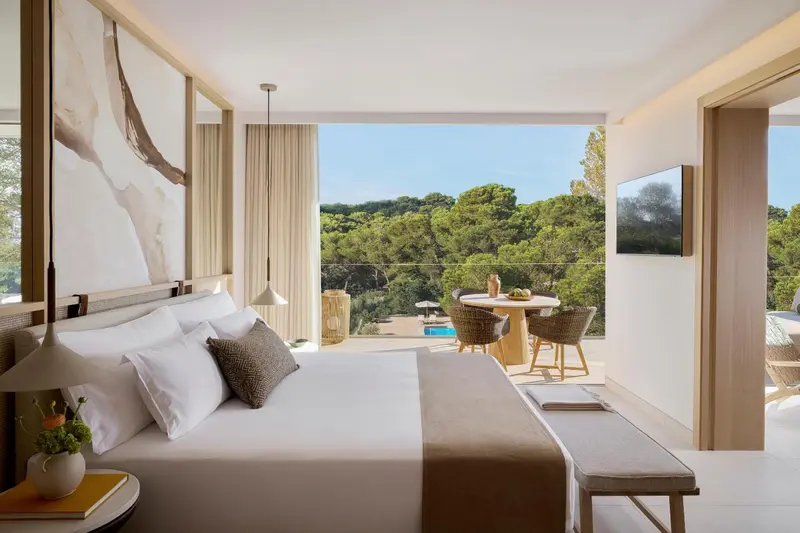 Une chambre lumineuse avec un grand lit et une vue sur la végétation.