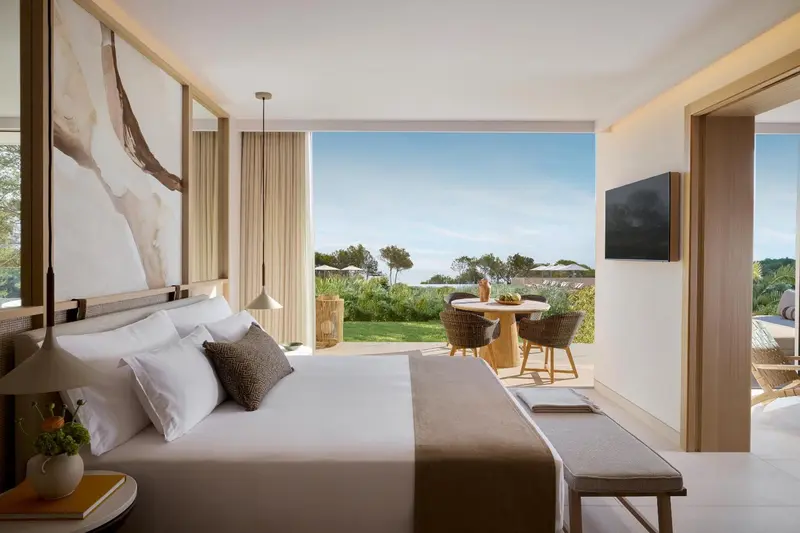 Une chambre lumineuse avec un grand lit donnant sur une vue verdoyante.