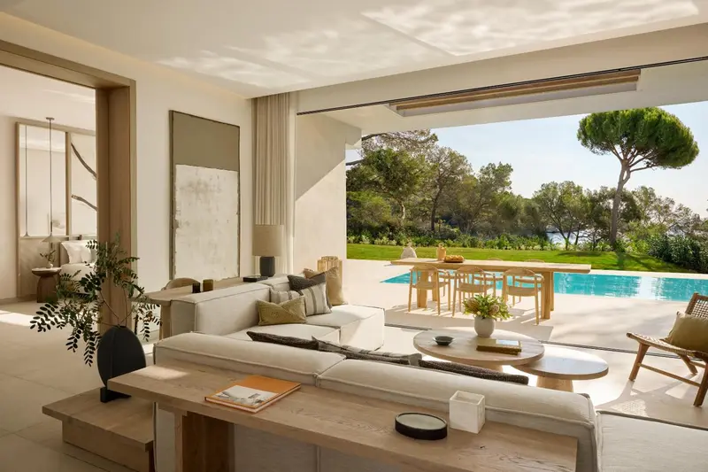 Un salon lumineux s'ouvre sur une terrasse avec piscine et vue sur la végétation.