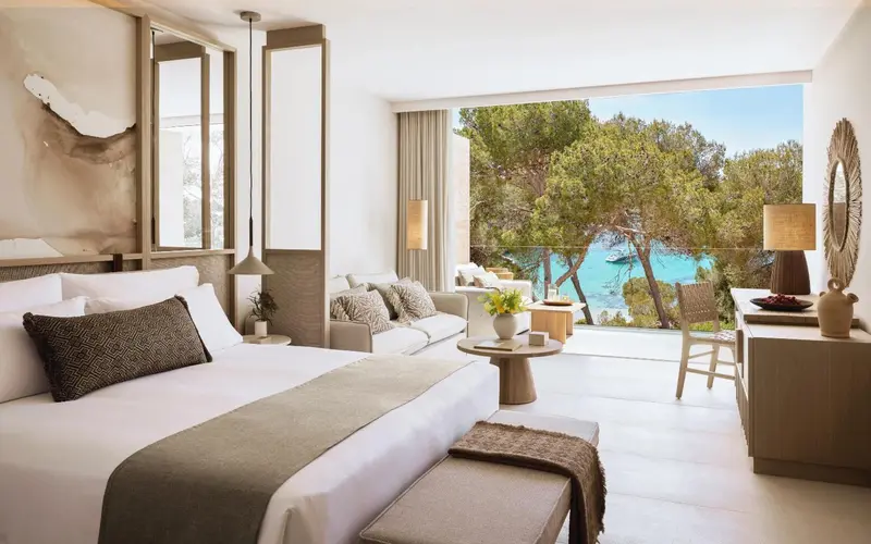 Une chambre lumineuse avec un grand lit et un coin salon donnant sur la mer.