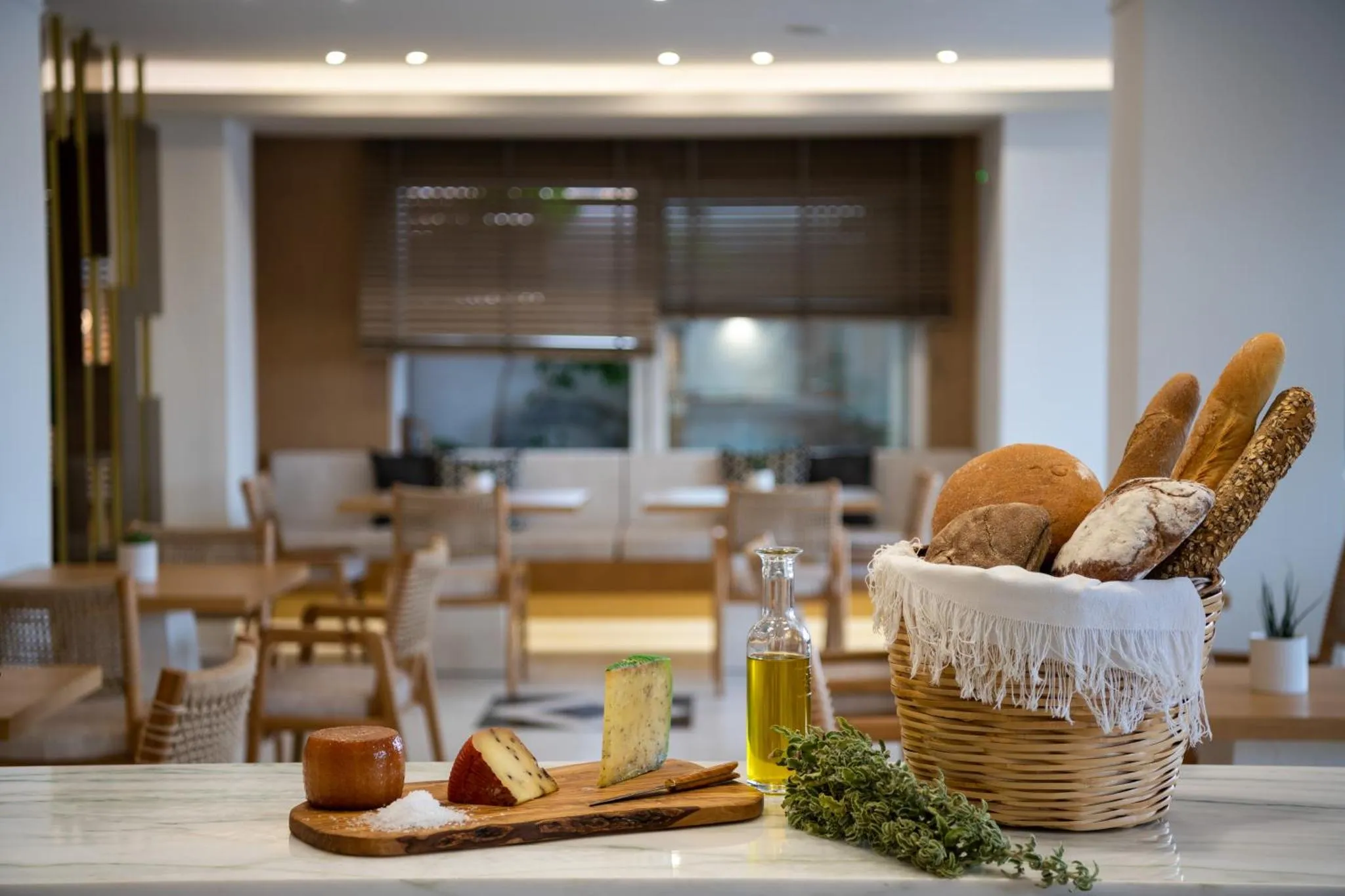 Une table en marbre présente une sélection de pains, de fromages et d'huile d'olive.