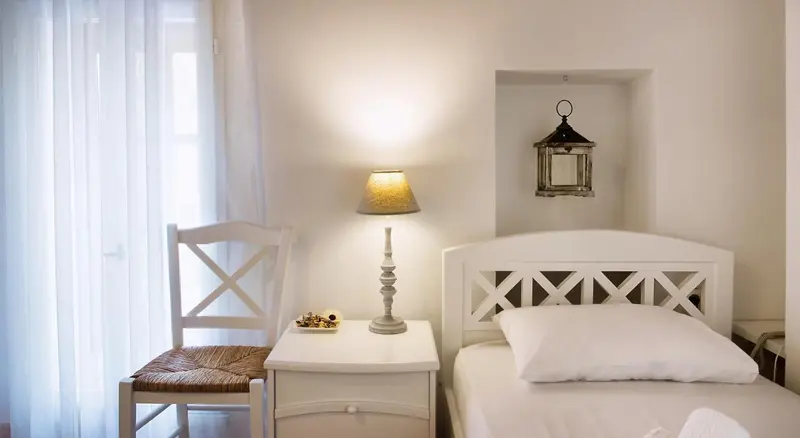 Une chambre lumineuse avec un lit simple et une table de chevet.
