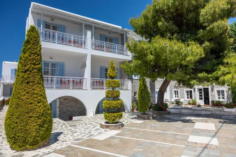 Bâtiment blanc à deux étages avec des balcons fleuris et une cour pavée.