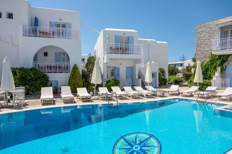Bâtiments blancs et transats au bord d'une piscine bleu turquoise.