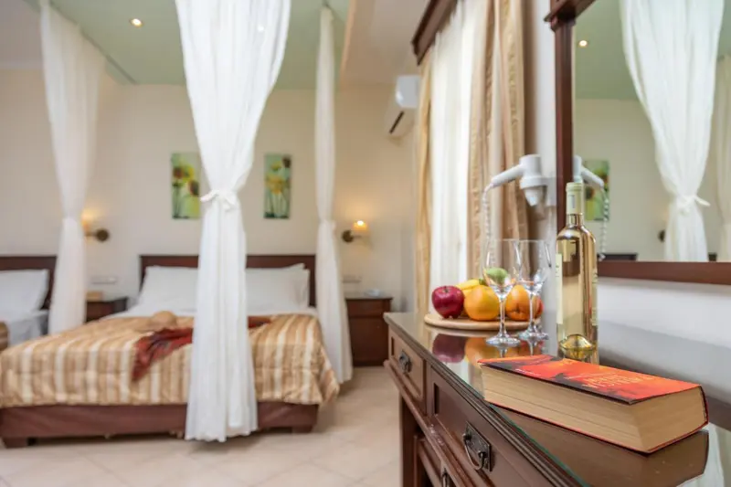 Une chambre à coucher lumineuse avec un lit à baldaquin et une table de chevet décorée de fruits et de livres.