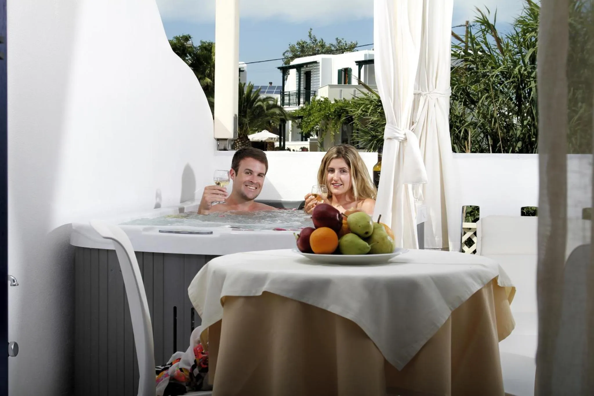 Un couple se détend dans un jacuzzi avec des fruits et des boissons.