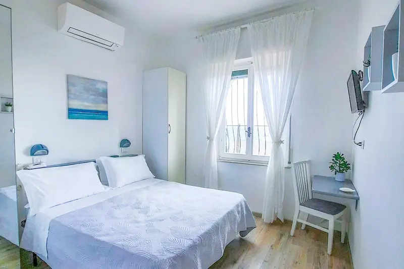 Une chambre lumineuse avec un lit fait et un bureau près de la fenêtre.