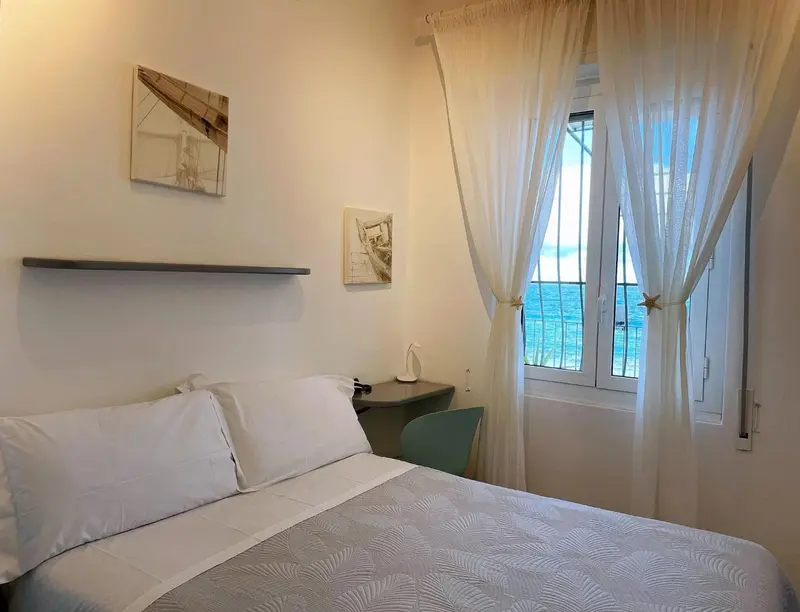 Une chambre lumineuse avec un lit fait et une vue sur la mer.