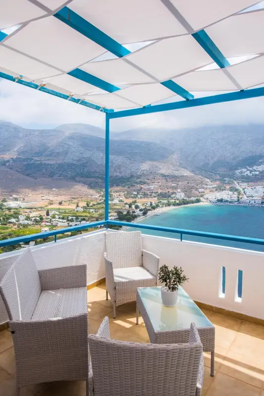 Terrasse aménagée avec mobilier en osier offrant une vue sur un paysage montagneux et la mer.