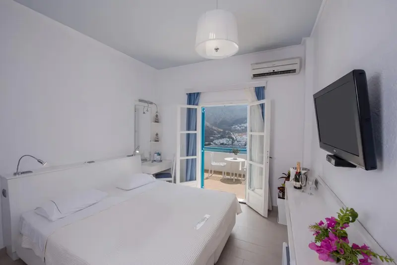 Une chambre lumineuse avec un lit blanc et une vue sur la mer.