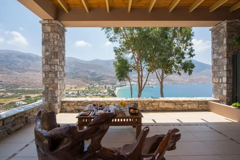 Une table est dressée sur une terrasse avec vue sur un paysage montagneux et la mer.