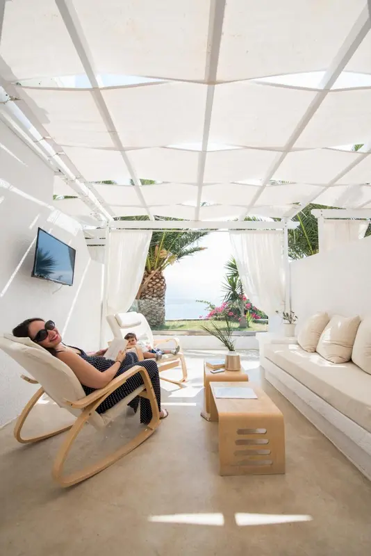Espace de détente extérieur avec mobilier blanc et vue sur la mer.