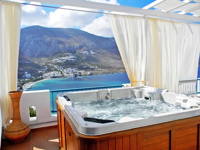 Un jacuzzi sur une terrasse offre une vue sur la mer et les montagnes.