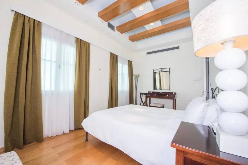 Une chambre lumineuse avec un lit blanc et des rideaux verts.