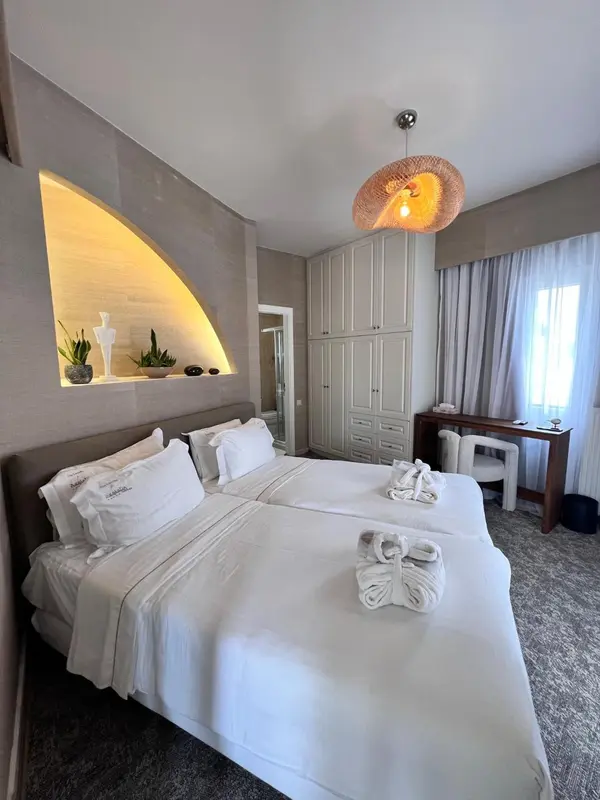 Une chambre lumineuse avec un grand lit recouvert de linge blanc.
