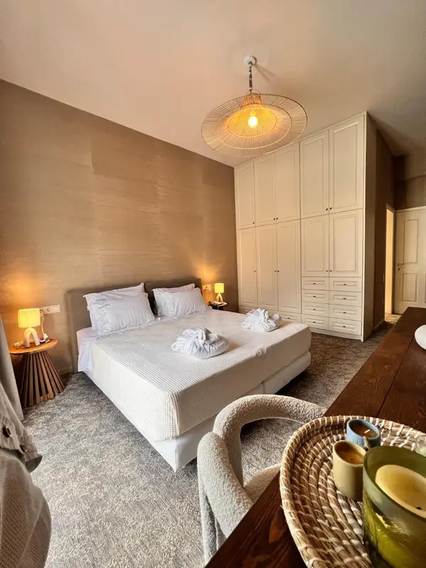 Une chambre à coucher lumineuse avec un lit fait et un coin repas en bois.