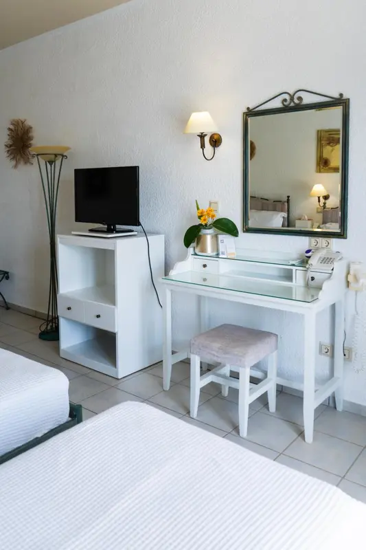 Une coiffeuse blanche avec un miroir et une chaise se trouve dans une chambre lumineuse.
